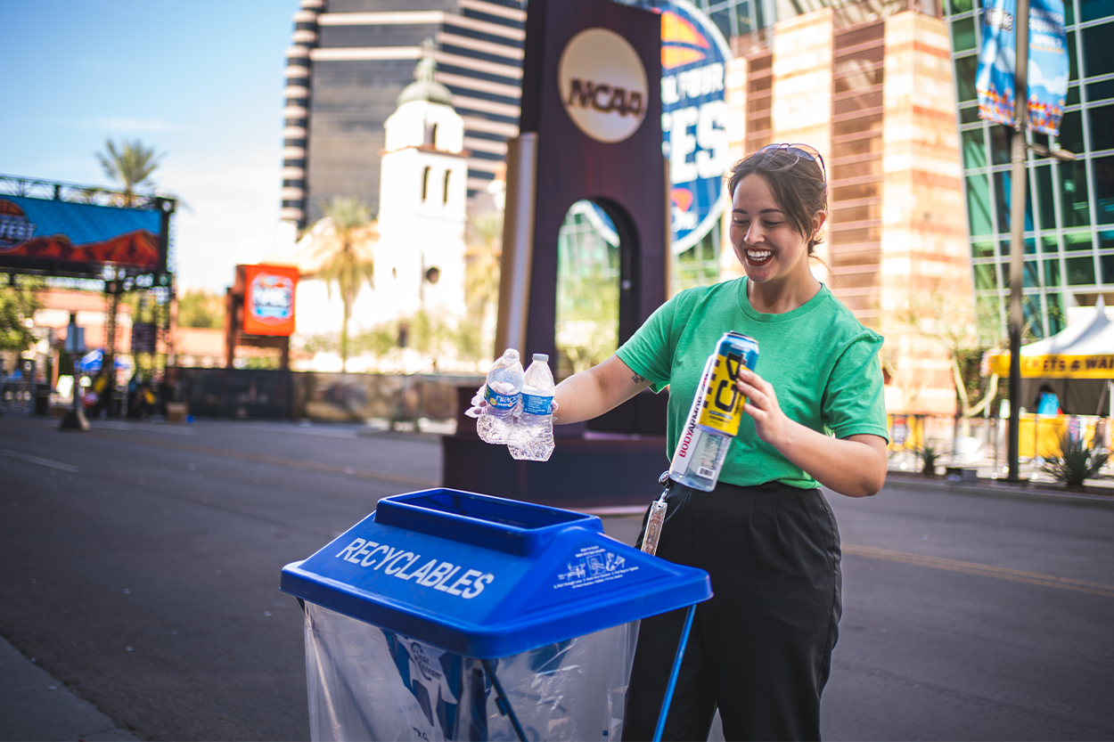 Person recyles at the Phoenix Convention Center in a recycling can. 
