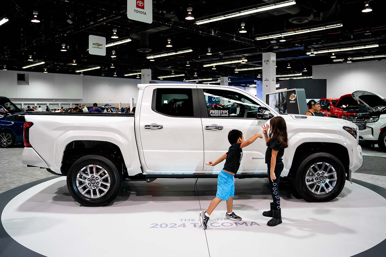 Truck on display for the International Auto Show with two kids playing in front of it 