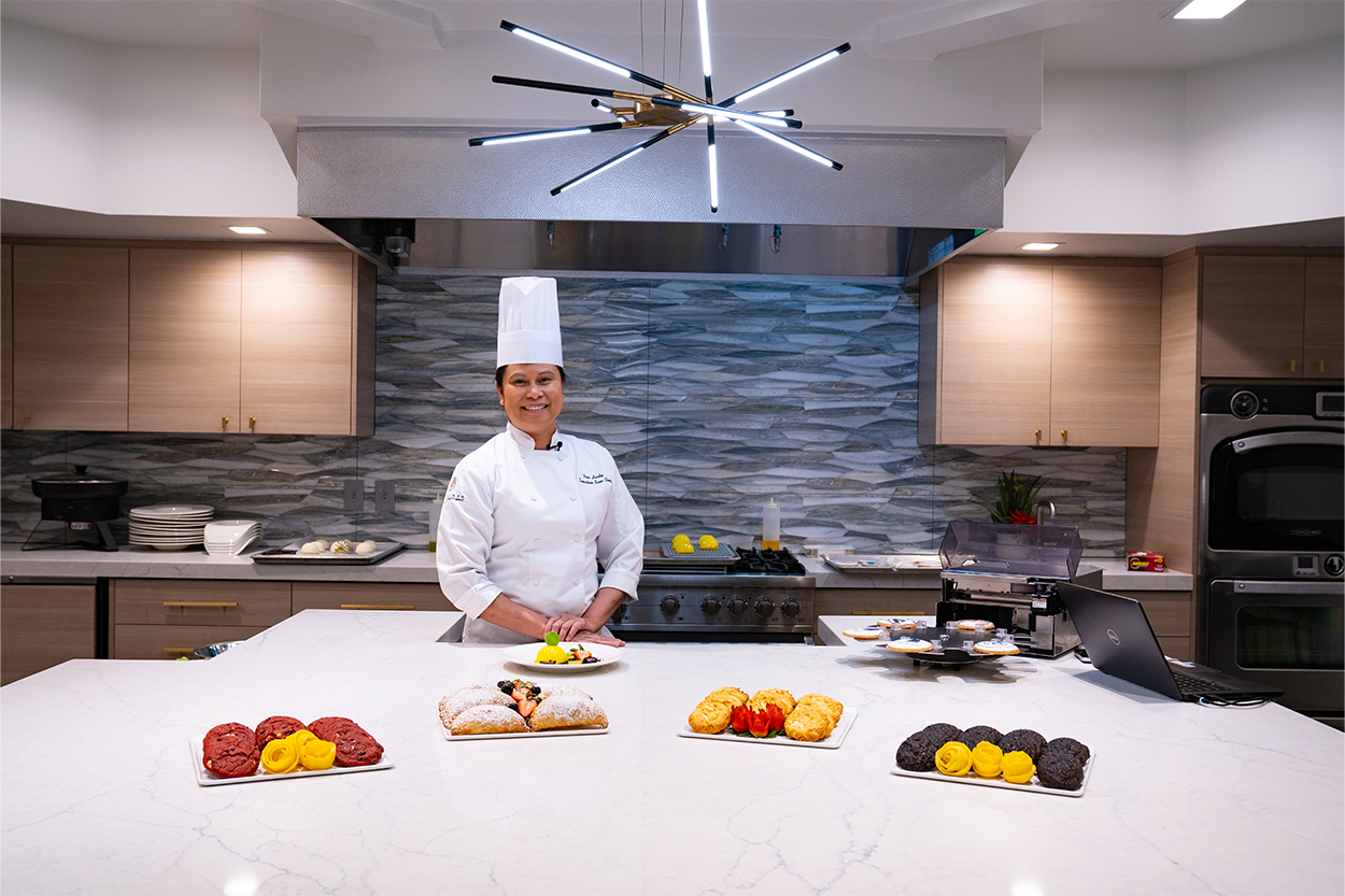 Chef standing in behind plated pastries in a kitchen