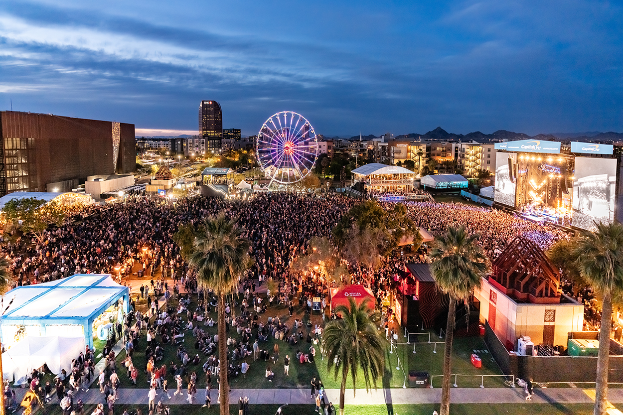 Musical event in a park with tents, a ferris wheel, and performance stage