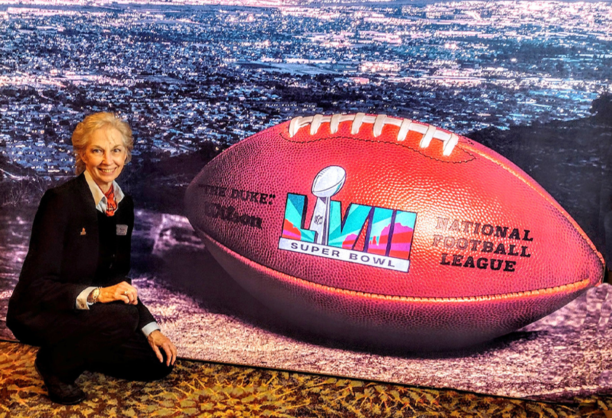Woman kneeling next to an oversized football prop