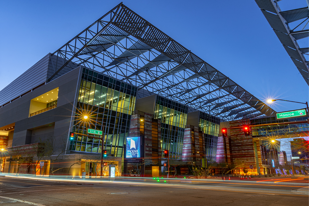 A nighttime view of the Phoenix Convention Center featuring its modern glass façade and steel canopy structure.
