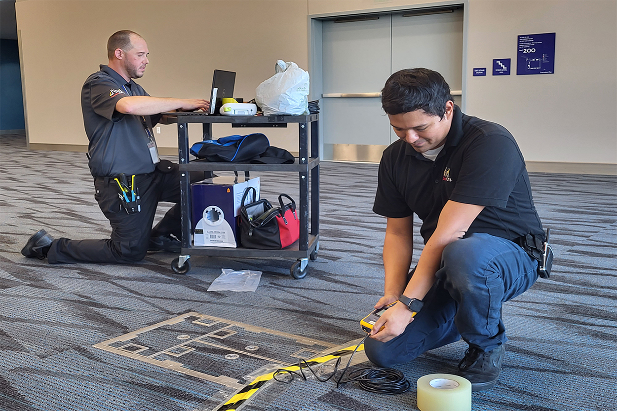 Workers installing telecommunication equipment on the event floor