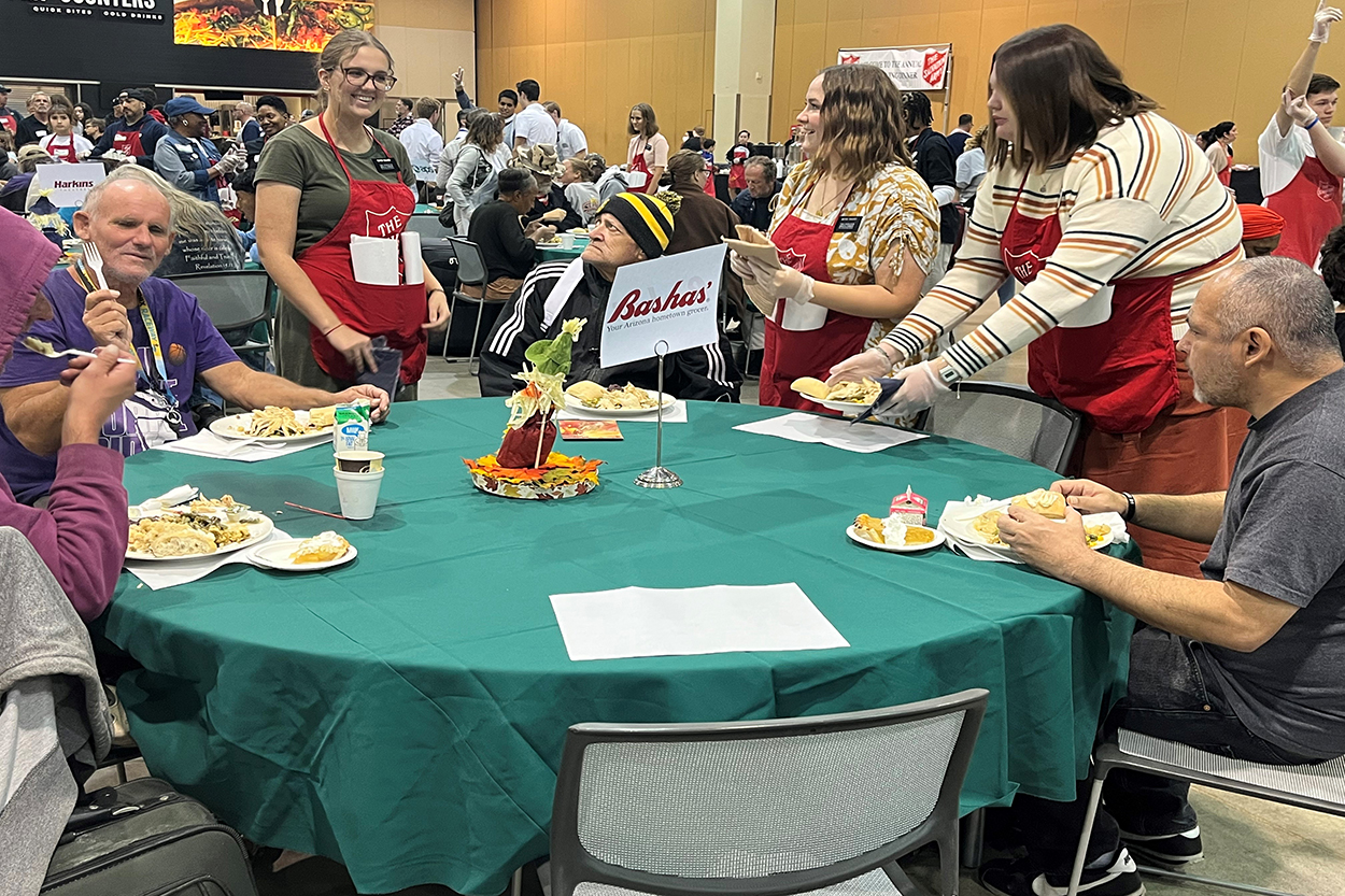 People seated around a table eating traditional Thanksgiving food
