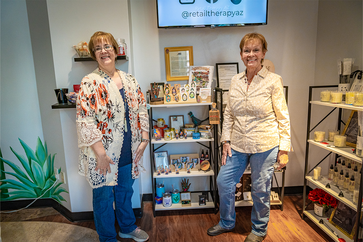 Two women pose with their bracelets for sale in a store 
